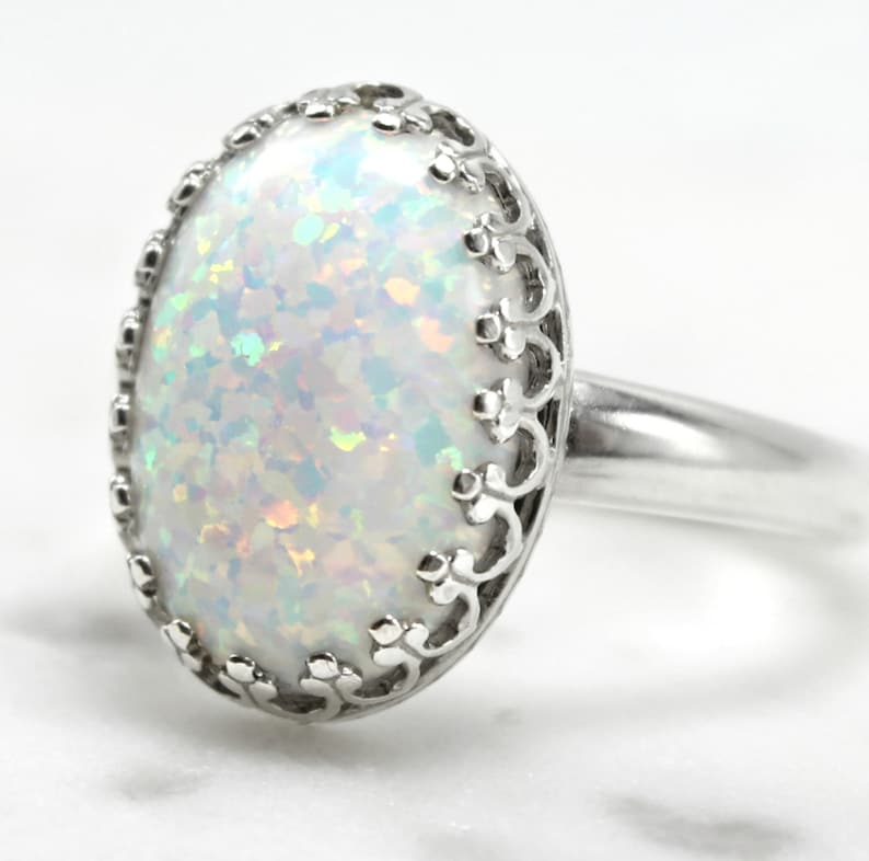 May include: A silver ring with a white opal gemstone set in a delicate filigree design.