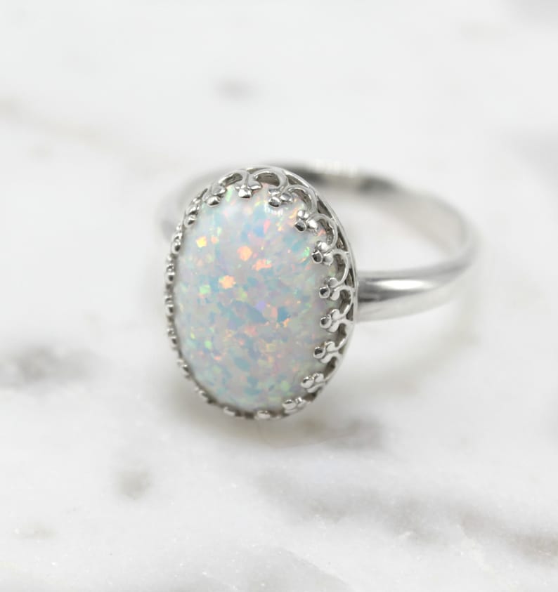 May include: A silver ring with a white opal gemstone set in a delicate filigree design.