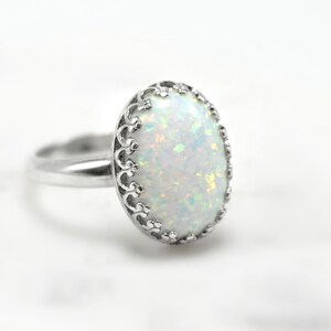 May include: A silver ring with a white opal gemstone set in a delicate filigree design.