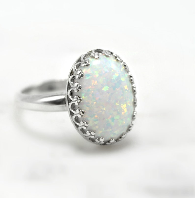 May include: A silver ring with a white opal gemstone set in a delicate filigree design.