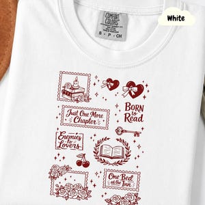 Peut inclure: T-shirt blanc à col rond et manches courtes. Le t-shirt présente des illustrations rouges de cœurs, de livres, de roses et les phrases "Born to Read", "Just One More Chapter" et "Enemies to Lovers".