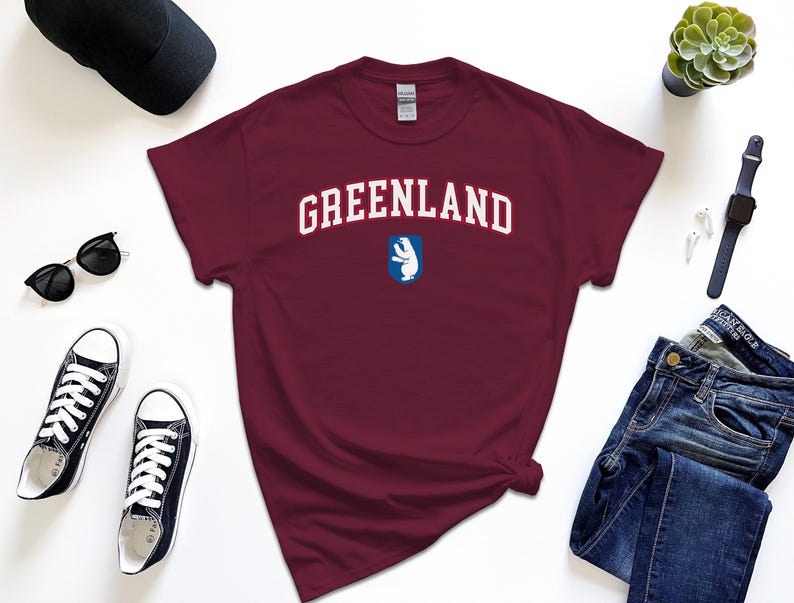 Op de afbeelding: Een maroon t-shirt met witte tekst die "GREENLAND" zegt en een blauwe en witte afbeelding van een ijsbeer.