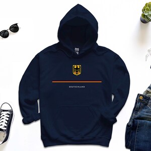 May include: A navy blue hoodie with a yellow and black German eagle logo and the word "DEUTSCHLAND" printed on the front.