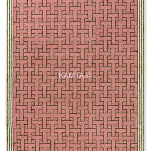 Puede incluir: Una alfombra rectangular con un patrón repetitivo de formas entrelazadas en tonos rosa y marrón. La alfombra tiene un borde con fondo crema y rayas verde oscuro. Es un revestimiento decorativo para el suelo.