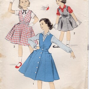 Könnte beinhalten: Vintage Schnittmuster mit Illustrationen von drei Mädchen in Kleidern. Die Kleider umfassen ein rot-weiß kariertes Kleid, ein graues Kleid mit rotem Tupfenoberteil und ein blaues Knopfkleid. Das Muster ist mit "ADVANCE" und "GRÖSSE 4" gekennzeichnet.
