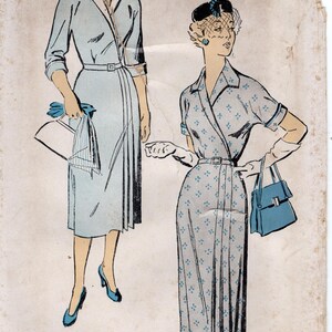 May include: Vintage New York Pattern sewing pattern featuring two dress designs. The dresses are light blue with belted waists. The pattern includes the text "NEW YORK PATTERN" and "Gold Seal Guaranteed Perfect".