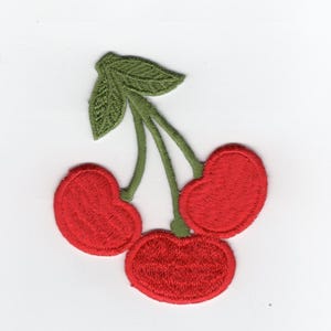 May include: Embroidered patch featuring three red cherries with green stems and a leaf. The cherries have a detailed, textured appearance, and the patch is likely designed for application on clothing or accessories.