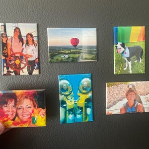 Puede incluir: Una colección de imanes rectangulares con varias imágenes. Un imán muestra a tres personas con un timón de barco. Otro presenta un globo aerostático sobre un paisaje. También se representan un perro, dos personas con trajes espaciales y dos mujeres.