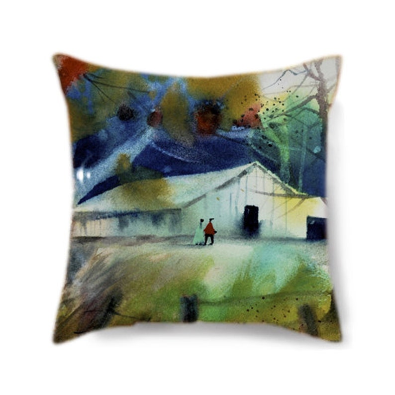 May include: Square decorative pillow featuring a watercolor painting of a building with two figures in front. The artwork uses shades of blue, green, and yellow, with a touch of red. The pillow has a white background.