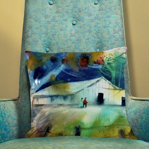 May include: A decorative pillow with an abstract painting of a white building, two figures, and a colorful landscape. The pillow is rectangular and rests on a teal armchair.