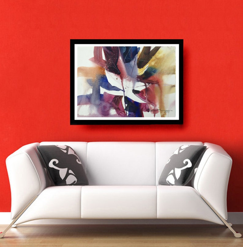 May include: Abstract watercolour painting in shades of purple, blue, brown, and white. The painting features a large, central leaf-like shape with smaller shapes surrounding it. The painting is framed in a black frame and is hanging on a red wall.