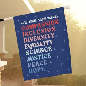 May include: A blue outdoor flag with the words "NEW YEAR. SAME VALUES." and the words "COMPASSION, INCLUSION, DIVERSITY, EQUALITY, SCIENCE, JUSTICE, PEACE, HOPE." in various colors. The flag is hanging on a white pole.