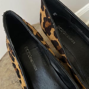 May include: A pair of BCBGeneration pumps featuring a textured leopard print pattern in shades of tan, brown, and black. The interior of the shoes is lined with black material, and the brand name BCBGeneration is printed in white on the black insoles.
