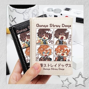 Puede incluir: Dos carteras, una negra y otra beige, con ilustraciones de estilo anime y el texto "Bungo Stray Dogs". La cartera beige tiene una cuadr&iacute;cula de cuatro paneles con arte de personajes.