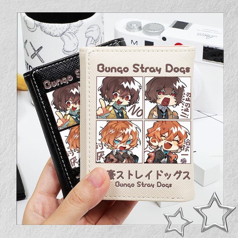 Puede incluir: Dos carteras, una negra y otra beige, con ilustraciones de estilo anime y el texto "Bungo Stray Dogs". La cartera beige tiene una cuadr&iacute;cula de cuatro paneles con arte de personajes.