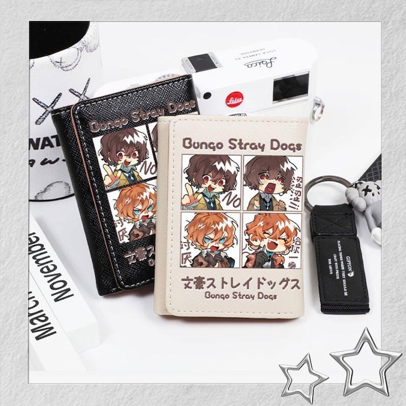 Puede incluir: Dos carteras y un llavero con personajes de anime. Una cartera es negra con costuras blancas y el texto "Bungo Stray Dogs". La otra cartera es blanquecina con el mismo texto y dise&ntilde;o de personaje. Tambi&eacute;n hay un llavero negro con un peque&ntilde;o peluche.