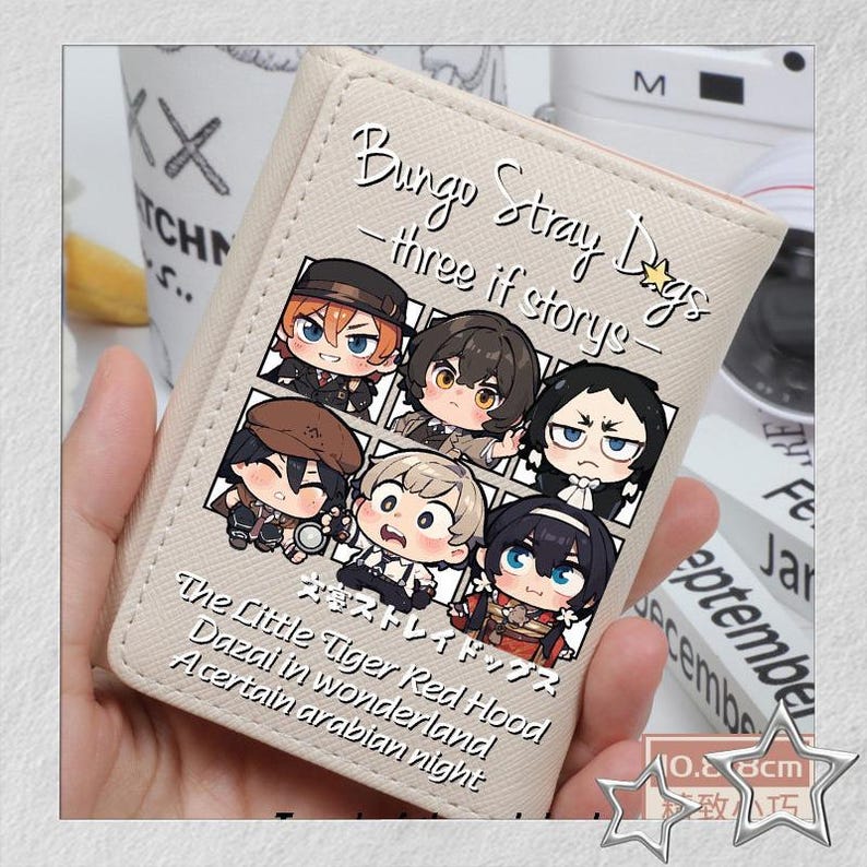 Puede incluir: Una cartera beige con ilustraciones de dibujos animados de personajes de "Bungo Stray Dogs". La cartera tiene el t&iacute;tulo de la serie y frases como "three if stories" y "The Little Tiger Red Hood" impresas. La cartera mide aproximadamente 10,8 cm.
