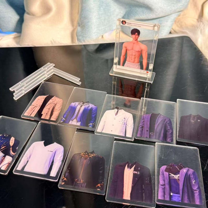 May include: A collection of clear acrylic cards featuring images of various jackets and blazers in different colors and styles. A clear acrylic stand holds a card with a shirtless man. The jackets include a white blazer, a purple blazer, and a black leather jacket.
