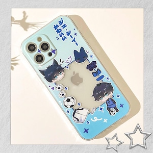 Peut inclure: Coque de t&eacute;l&eacute;phone transparente avec un bord bleu clair et un motif de personnages de style anime, de ballons de football et de texte japonais. L'&eacute;tui a un centre transparent, mettant en valeur le logo Apple du t&eacute;l&eacute;phone.