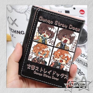 Puede incluir: Cartera negra con una ilustraci&oacute;n de cuatro paneles de personajes de anime. La cartera tiene el texto "Bungo Stray Dogs" y texto japon&eacute;s. La cartera mide aproximadamente 10,8 cm de ancho.