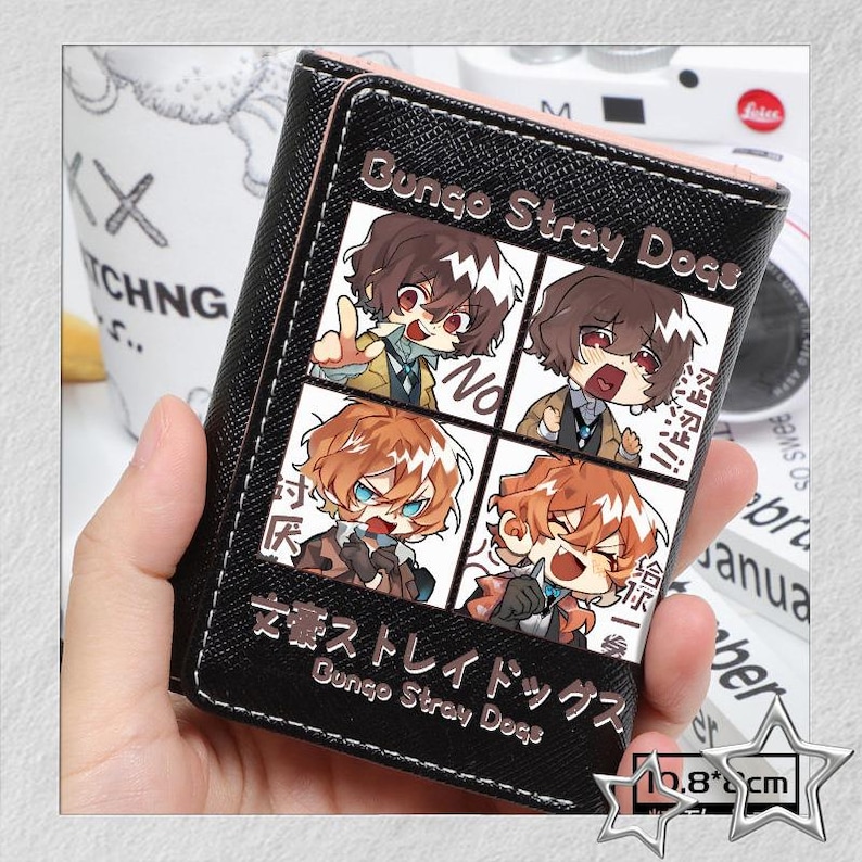 Puede incluir: Cartera negra con una ilustraci&oacute;n de cuatro paneles de personajes de anime. La cartera tiene el texto "Bungo Stray Dogs" y texto japon&eacute;s. La cartera mide aproximadamente 10,8 cm de ancho.