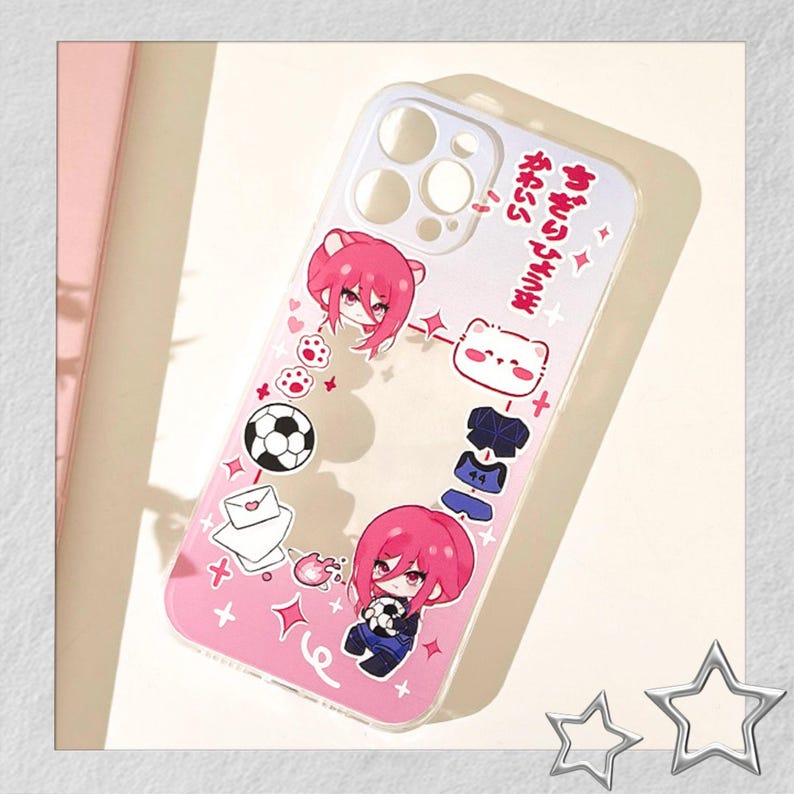 Peut inclure: Coque de t&eacute;l&eacute;phone transparente avec un design rose et blanc. La coque pr&eacute;sente des illustrations de dessins anim&eacute;s d'un ballon de football, de personnages aux cheveux roses et du texte japonais. La coque a une bordure transparente et un fond rose.