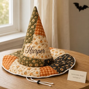 May include: A quilted witch hat featuring a patchwork design of orange, cream, and dark green fabrics with floral and pumpkin patterns. The hat displays the name Harper in dark brown script and includes a white drawstring with a black toggle.