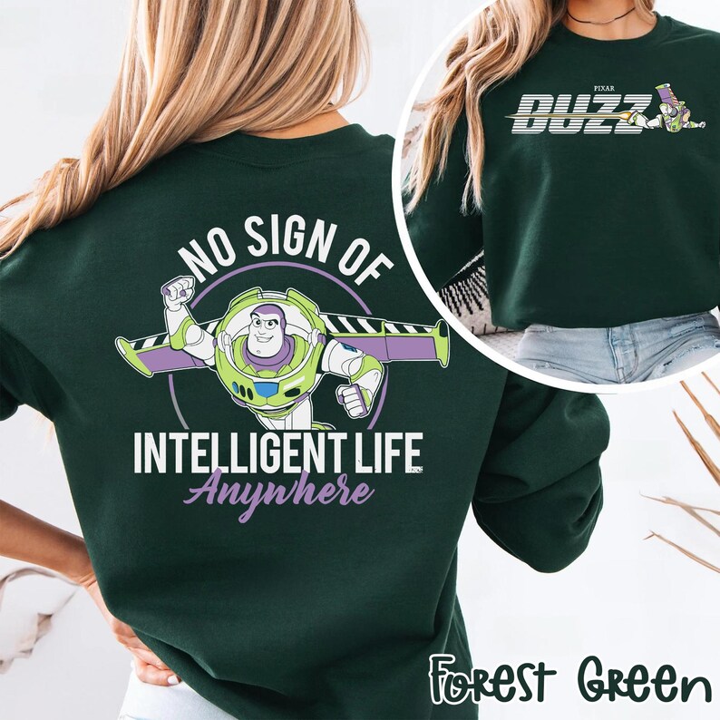 May include: Forest green sweatshirt featuring Buzz Lightyear with the text "NO SIGN OF INTELLIGENT LIFE ANYWHERE." The design includes a cartoon image of Buzz Lightyear in his space suit. The upper right corner shows the word "BUZZ" and a cartoon image.