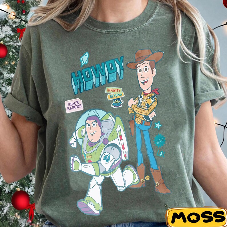 Peut inclure: T-shirt vert olive avec les personnages de dessins anim&eacute;s Buzz l'&Eacute;clair et Woody de Toy Story. Le t-shirt porte l'inscription "HOWDY" et les phrases "SPACE RANGER" et "INFINITY BEYOND". Le t-shirt porte &eacute;galement le mot "WOW".