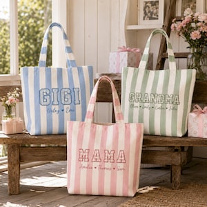 May include: Three canvas tote bags with vertical stripes in light blue, sage green, and soft pink. Each bag features embroidered text: GIGI with names Haley and Emi, GRANDMA with names Oliver, Emily, Carter, and Julia, and MAMA with names Amelia, Thomas, and Sam.