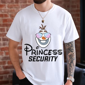 以下が含まれることがあります： サングラスをかけたオラフの漫画のイメージがプリントされた白いTシャツ。「Princess Security」の文字が下にスタイリッシュなフォントでプリントされています。半袖のシャツです。