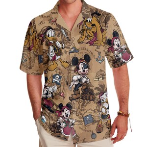 May include: A brown short-sleeved button-down shirt with a tropical print featuring Mickey Mouse, Donald Duck, and Goofy characters. The print includes a treasure map design with the text "TREASURS" and "TRITATERA".