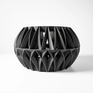 May include: A black geometric planter with a unique, intricate design. The planter is made of a durable material and has a modern, minimalist aesthetic.
