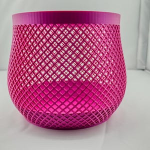 May include: A pink, mesh planter with a diamond pattern. The planter is made of a durable plastic material and is perfect for adding a touch of color to your home decor.
