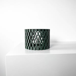 May include: A dark green cylindrical planter with a honeycomb pattern. The planter is made of a durable material and has a modern design.