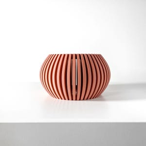 May include: A terracotta colored, round, wooden planter with a slatted design.