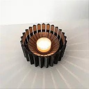 May include: A black wooden candle holder with a circular design. The holder has a small, round opening in the center for a tea light candle.