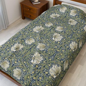 May include: A bedspread with a floral design in green, cream, and navy blue. The pattern includes large, stylized flowers and leaves, offering a classic, elegant aesthetic. The bedspread is on a wooden bed frame.