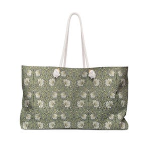 Peut inclure: Grand sac fourre-tout avec un motif floral vert et blanc. Il est doté de poignées en corde blanche et d'éléments décoratifs blancs. Le motif floral se répète sur toute la surface du sac. Idéal pour transporter des articles.