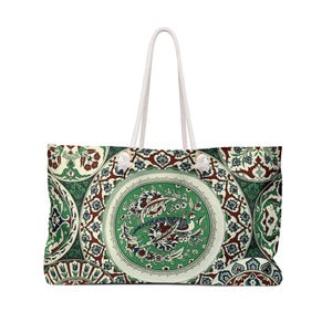 Könnte beinhalten: Eine große Tragetasche mit einem sich wiederholenden kreisförmigen Muster in Grün-, Dunkelrot- und Weißtönen. Das Design umfasst komplizierte Blumenmotive und eine zentrale Vogelillustration in jedem Kreis. Die Tasche hat zwei weiße Seilgriffe.