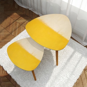 May include: Two yellow and white ombre nesting tables with a triangular shape and wooden legs.