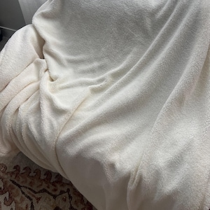 May include: A white fluffy blanket draped over a chair. The blanket is soft and plush, perfect for cuddling up on a cold day.