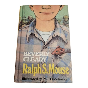 Pode incluir: Uma capa de livro com uma camisa xadrez azul e branca com um rato castanho espreitando do bolso. O título do livro é "Ralph S. Mouse" de Beverly Cleary, ilustrado por Paul O. Zelinsky.