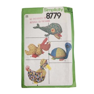 May include: A vintage Simplicity pattern envelope, featuring illustrations of four stuffed animal designs: a whale, a pelican, a turtle, and a duck. The envelope is green with the number 8779 and the text "NO EXCHANGES OR REFUNDS ON PATTERNS".