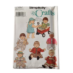 Op de afbeelding: Een Simplicity Crafts patroonhoes met illustraties van babypoppen in verschillende outfits. De envelop heeft de tekst "Simplicity Crafts" en het patroonnummer 7992. De poppen dragen jurken, rompertjes en hoeden.