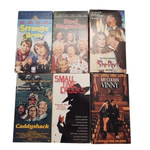 Puede incluir: Una colección de seis cintas VHS con títulos de películas como "Strange Brew", "Steel Magnolias" y "She-Devil". Las cintas muestran portadas coloridas con actores y títulos de películas. La colección incluye comedias y dramas.