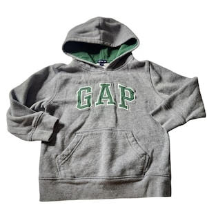 May include: Gray hooded sweatshirt with the word "GAP" in green block letters across the chest. The hood has a green lining. The sweatshirt has a front pocket and ribbed cuffs.