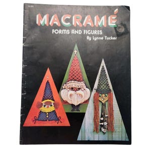 May include: A vintage macrame book titled "Macrame Forms and Figures" by Lynne Tucker. The cover features three macrame figures within triangular frames: a gnome, a bearded figure, and a witch with long orange hair, all against a black background.
