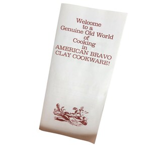 May include: A white paper with the text "Welcome to a Genuine Old World of Cooking in AMERICAN BRAVO CLAY COOKWARE!" in maroon. A maroon illustration of vegetables is at the bottom.