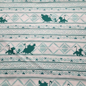 Puede incluir: Tela blanca con un patrón repetido de formas geométricas verdes y siluetas de un jabalí y un león corriendo.